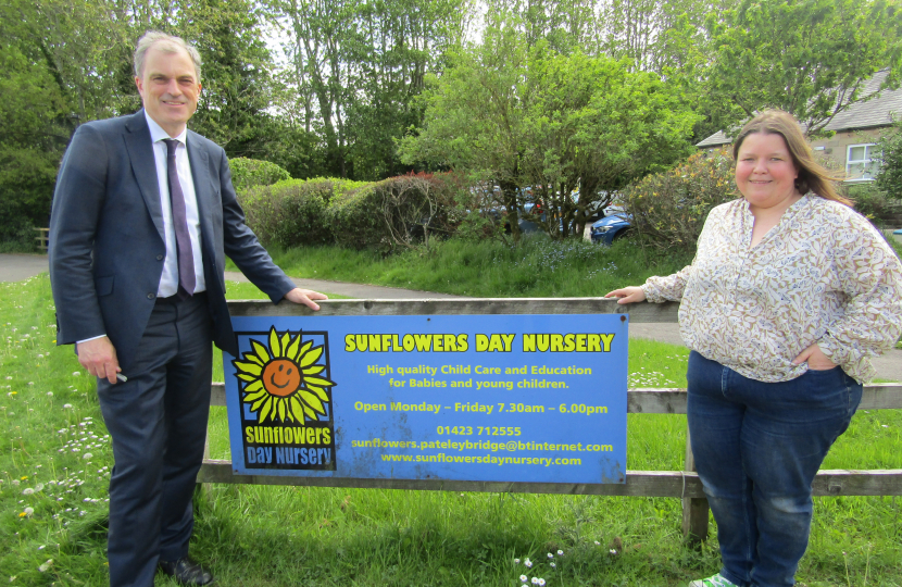 Julian and Heather standing next to the Sunflowers Day Nursery sign